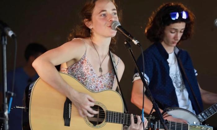 Cori Moore on stange with guitar, and a person backing her on banjo