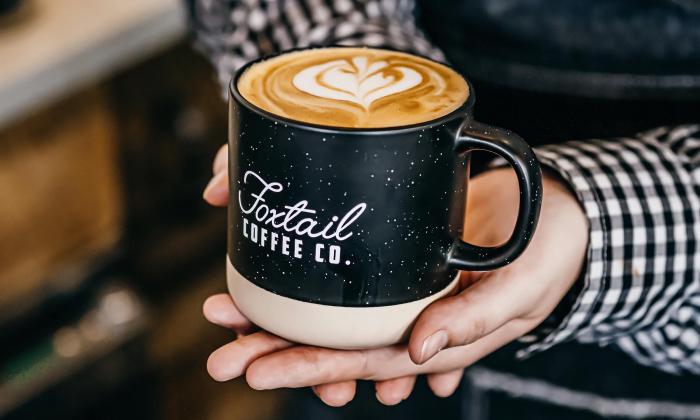 A hot latte served in a Foxtail branded mug