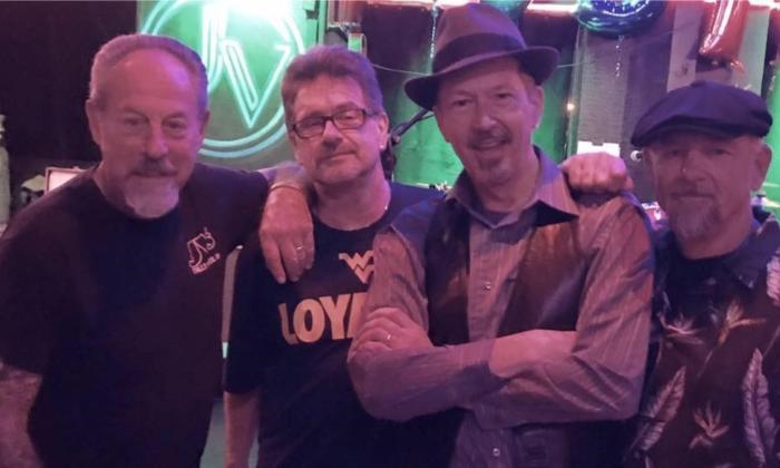 Bandmates from The Nighthawks smile and pose in front of a green backdrop.