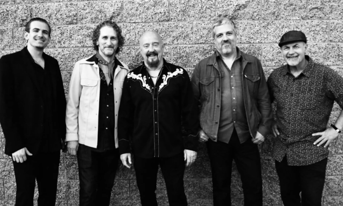 Bandmates from The Fabulous Thunderbirds pose in front of a textured wall.