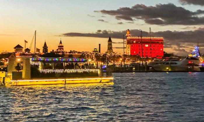 The brightly lit tour boat for Florida Water Tours cruising past the red-light-reflectingTreasury Building, 