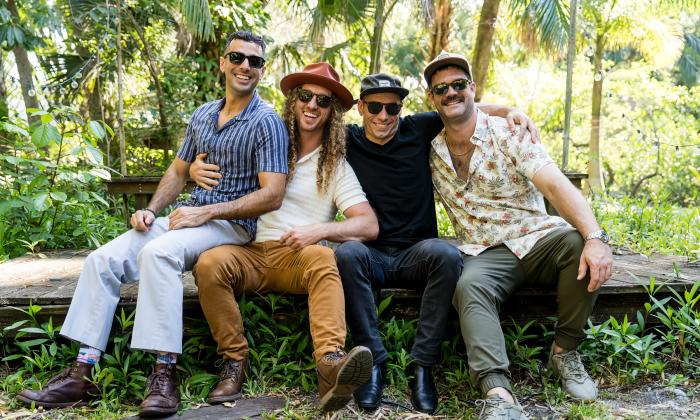 The four members of Honey Hounds sitting on a log in the forest