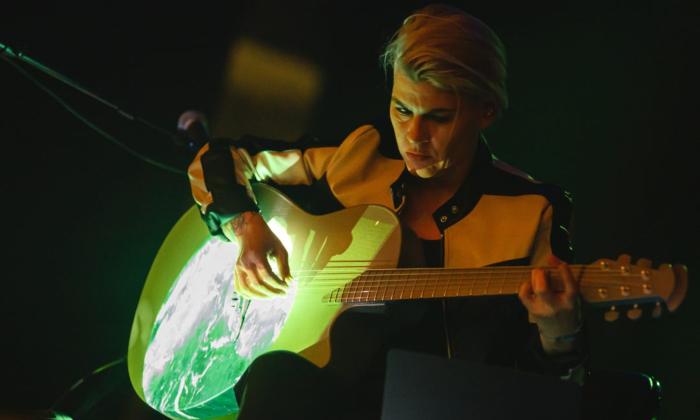 Kaki King strums her guitar on stage.