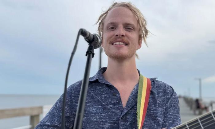 Righteous Roots leader Tom Leighton standing with guitar, outside