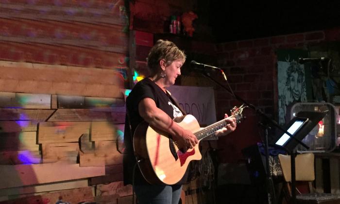 singer songwriter Sandi Dotson-Kirn playing guitar onstage