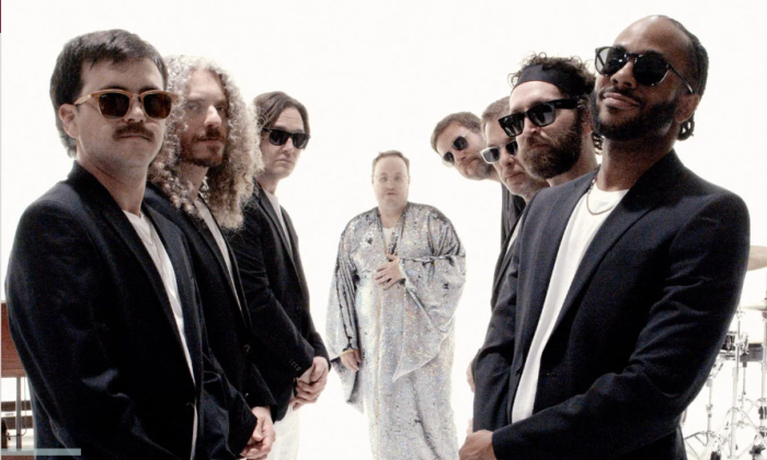 Bandmates from St. Paul & The Broken Bones wear dark clothing and pose in front of a white backdrop.