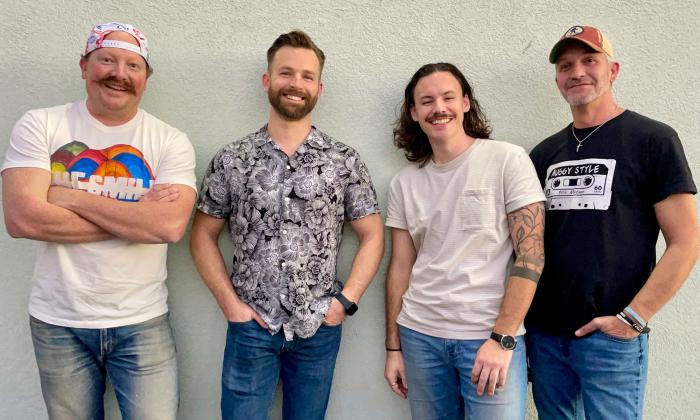 Tha band Auggy Style standing together in front of a white wall.