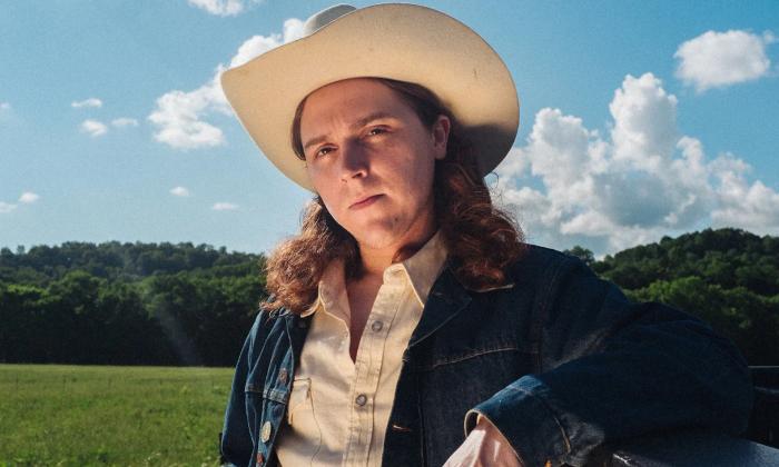 Daniel Donato stands in his cowboy hat against a backdrop of open sky and rolling green hills.
