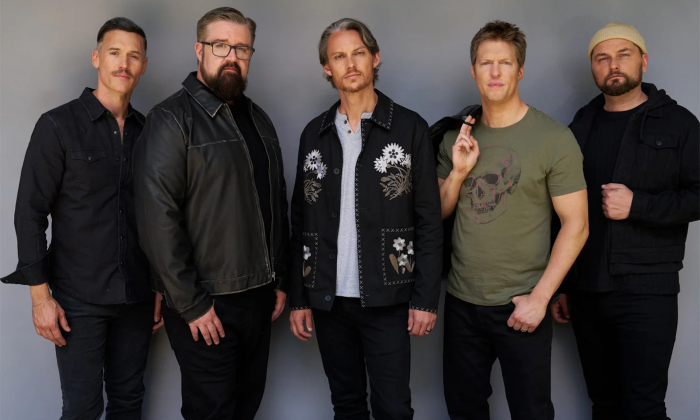 Bandmates from Home Free wear dark clothing and pose in front of a gray backdrop. 