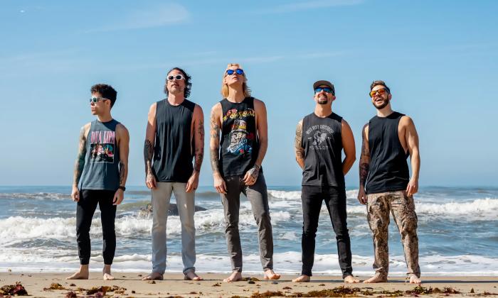 The band Ballyhoo on the beach with waves behind them