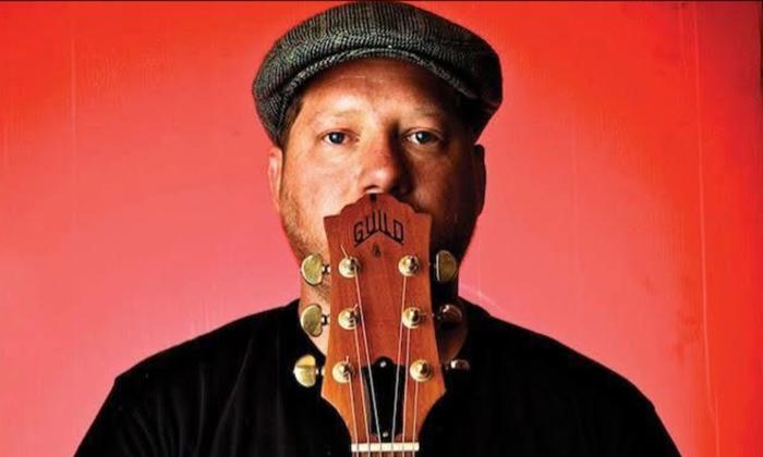 Musician Beau Crum holding guitar upright in front of his mouth