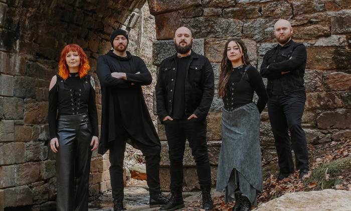 Members of SYR, a 5-person Celtic band, wearing black in front of an old fort or castle