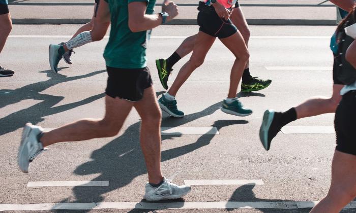 Race runners along a road, seen from the waist down
