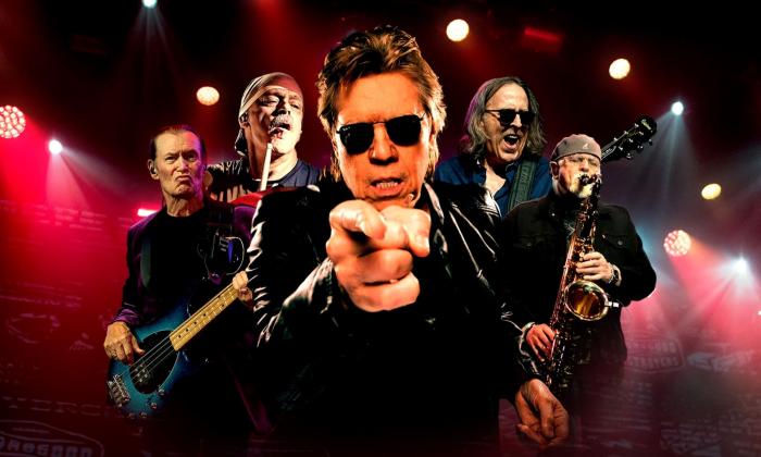 George Thorogood and The Destroyers pose and perform on stage.