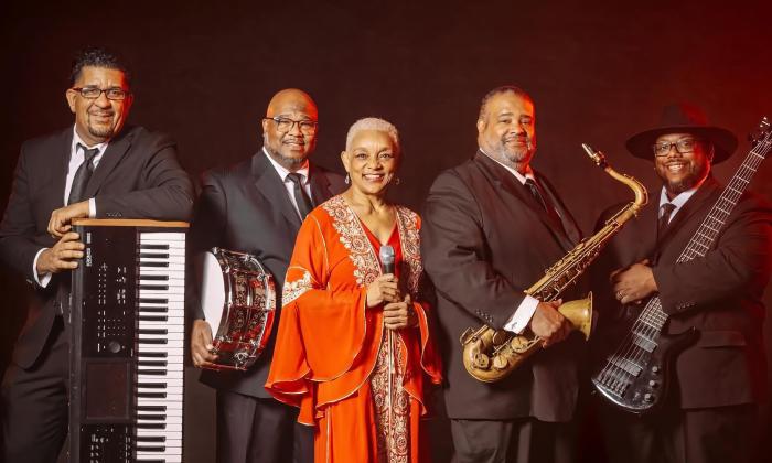 The five members of The Myrna Clayton Experience, with Myrna in the center wearing red
