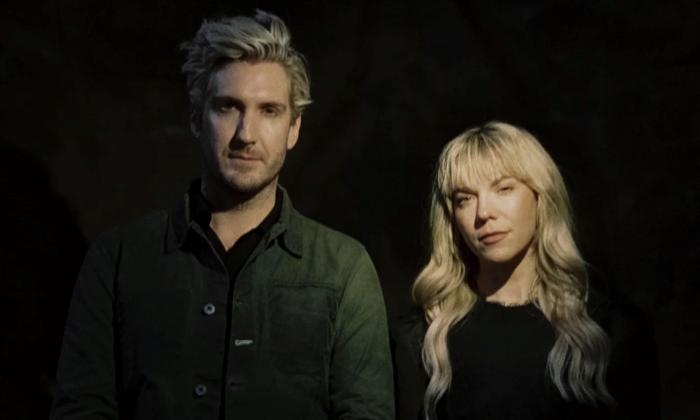 Bandmates from The Band Perry pose in black clothing in front of a black backdrop.