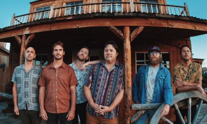 Bandmates from Iration pose in front of an Western-styled saloon.