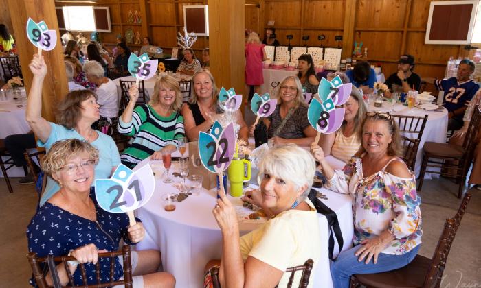 Women at a round banquet table holding their paddles