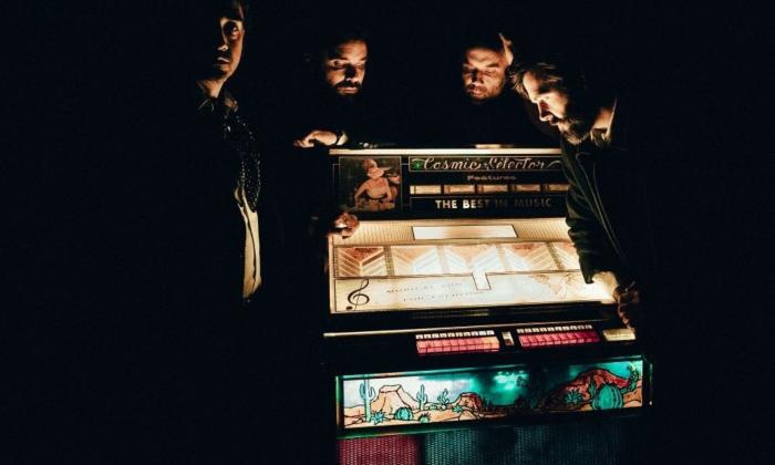 Bandmates from Lord Huron pose in front of a jukebox. 