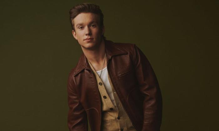 Ty Myers poses in front of a dark green backdrop. 