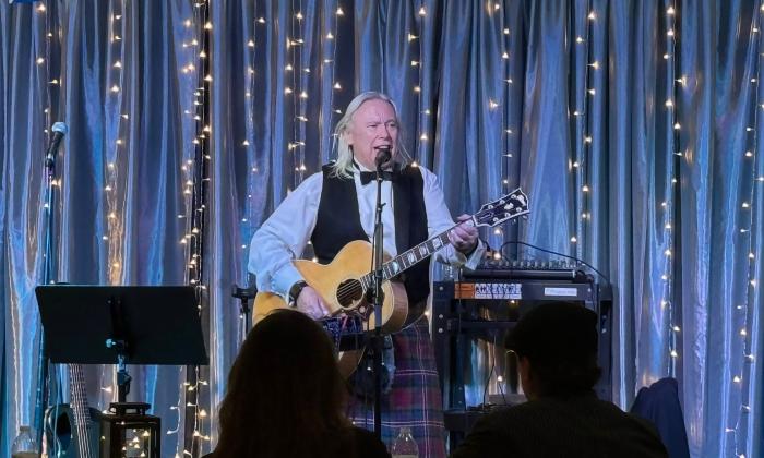 Bill Mullen on stage with his guitar, in front of a live audience