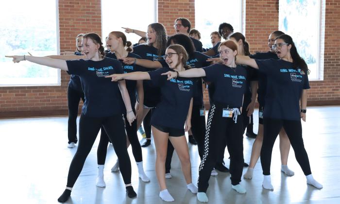 A troup of young dancers and singer performing in a hallway