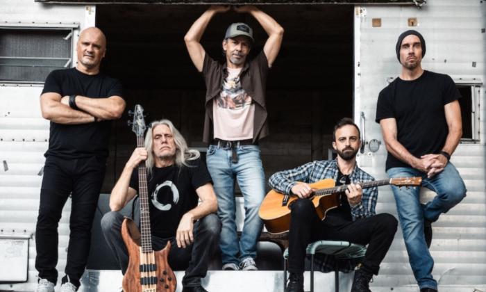 Bandmates from Given to Fly pose with their musical instruments.