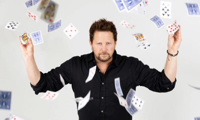 Andy Gross poses with cards that float from his hands.