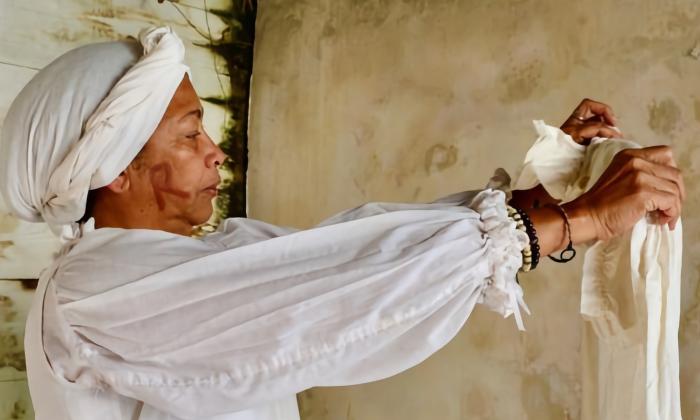 An actor protraying an enslaved woman doing laundry