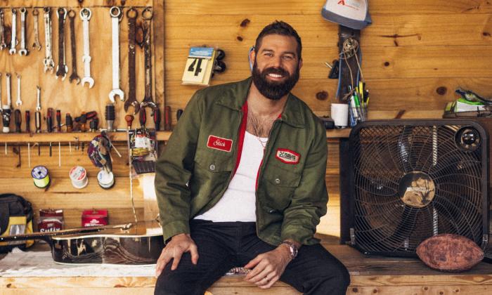 Jordan Davis smiles and poses in front of a tool shed. 