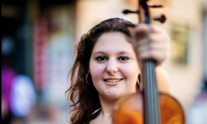 Ilana Zaks-Nederlander holding her violin upright in front of her