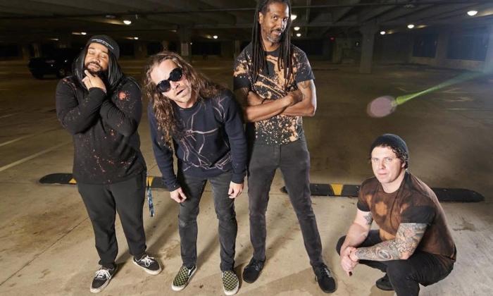 Bandmates from Heart Shaped Box wear black clothing and pose in a parking lot. 