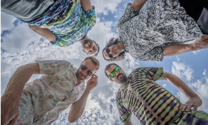The members of Spafford, dressed in colorful shirts, pose while looking down toward the camera, creating a fun and distinctive perspective.