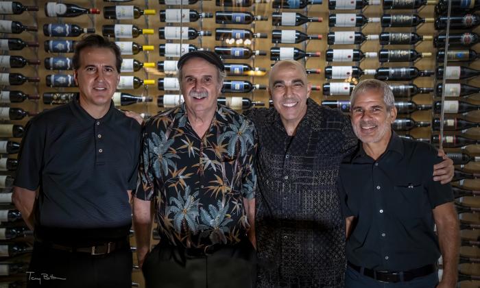 House Cats band in front of a wall of sine bottles. Photo courtesy of Terry Bottom photography