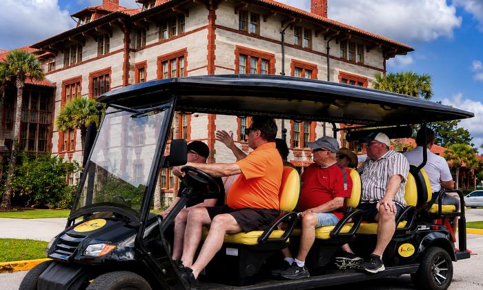 A guide with passengers in a First Coast Cart Tours History Tour in front of Flagler College
