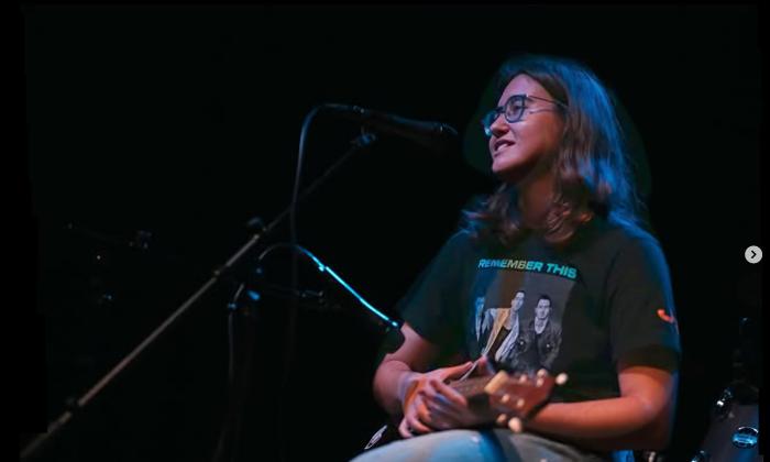 Juliana Messina on a dark stage with her ukelele