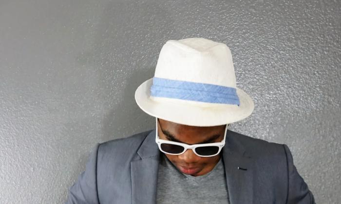 King Whale, musician, with his head bowed, wearing a white hat with blue band