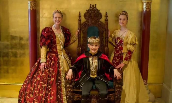 Two women in Spanish colonial garb, standing on either side of a young man dressed as the Spanish King