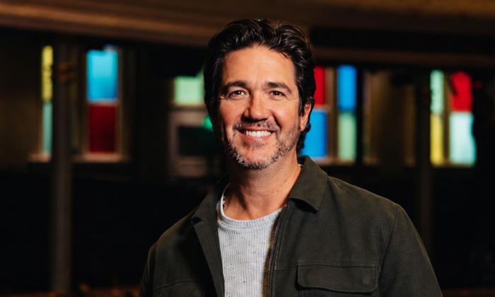 Songwriter Chris Blaire, smiling, with stained glass lights behind