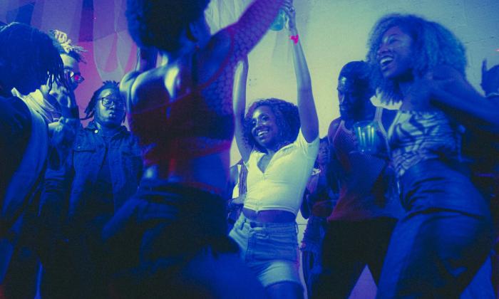 Partygoers raise their hands and dance excitedly. 