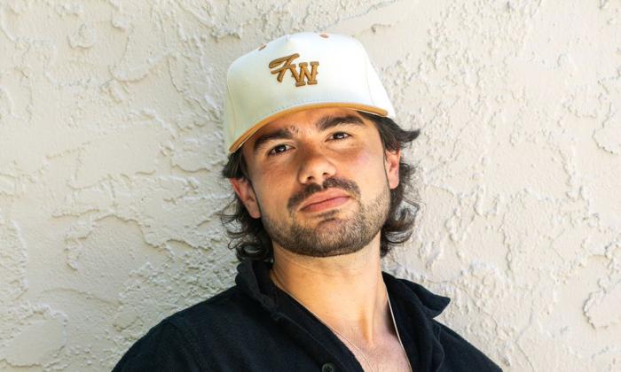 Composer Emmett Stevens, Jr standing in front of white wall, in a ball cap