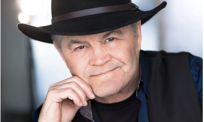 Micky Dolenz wears a black hat with matching blazer and poses for fans. 
