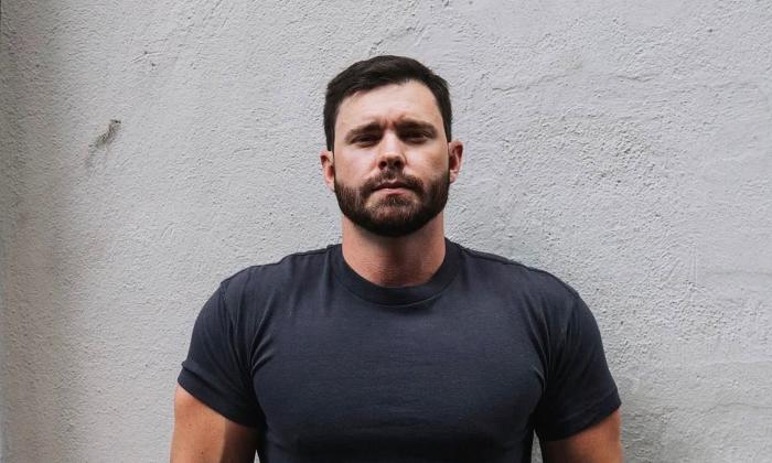Songwriter Murphy Elmore standing in front of white wall