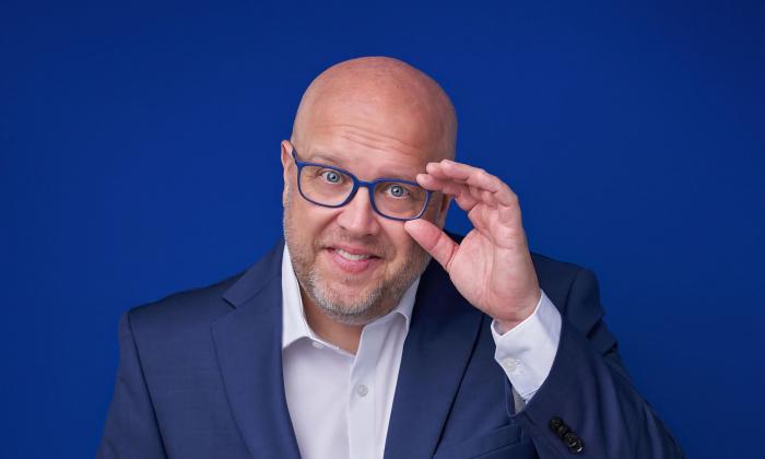 Comedian Danny Johnson, in a blue suit with blue glasses