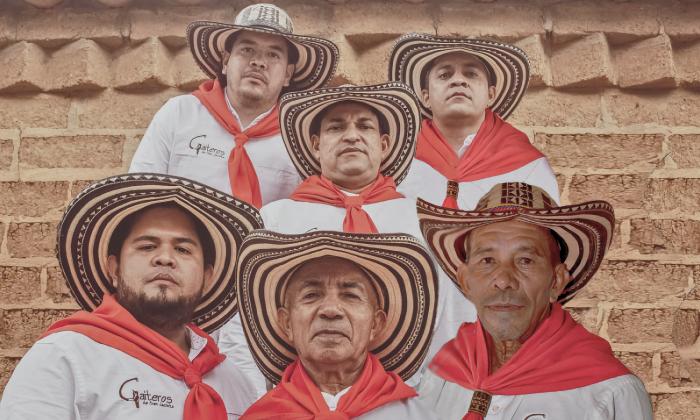 The five musicians of Los Gaiteros de San Jacinto, wearing white shirts, red bandanas, and traditional hats