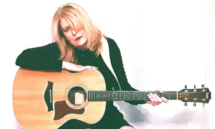 Sparrow Smith (Kathi Witkowski) with her guitar sitting against a white background