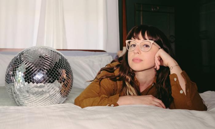 Musician Tierney Tough, on a bed next to a disco ball