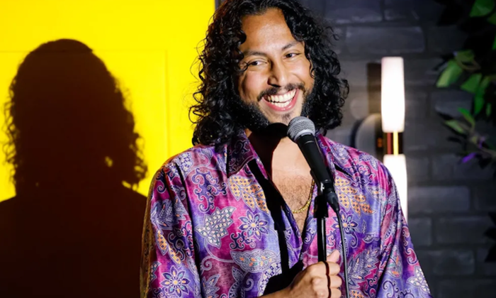 Wyatt Feegrado smiles and performs for the audience in front of a bright yellow backdrop.