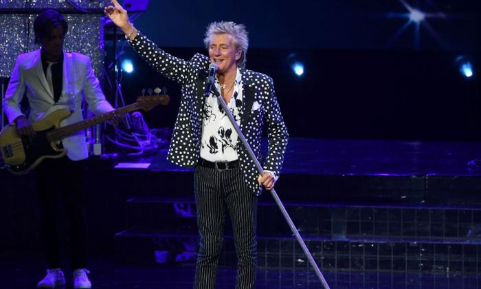 Rod Stewart performs on stage for fans.