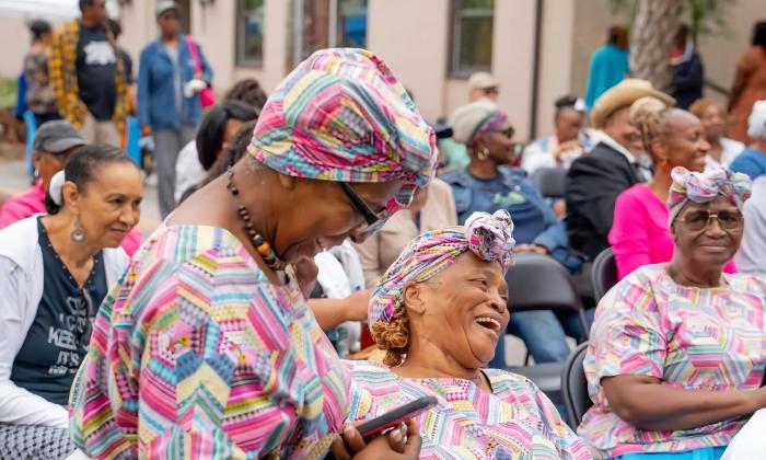 Women in Gullah Geechee traditional dress among an audience at an event